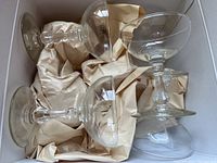 Box containing 4 of the Mikasa stemmed glasses packed with paper cushioning.