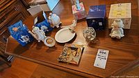 Overview of all items on wooden table showing figurines, plates, glass bowl with pewter lid, and Regency Rose teapot and canister