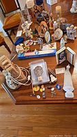 Overview of the full lot showing religious figurines, icons, crosses, candles, and nativity lamp on wooden table.