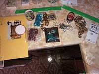 Top view of 10 assorted rosaries and a rosary case on kitchen counter.