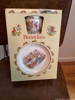 Original box showing the Royal Doulton Bunnykins children's 3 piece set including cup and plate visible through cutouts with rabbit decorations on the box.