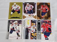 Seven Alexander Ovechkin hockey cards laid out on flat surface in two rows. Various designs and themes.