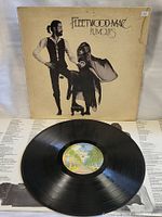 Vinyl record partially out of the cover showing the label and inner liner notes behind.