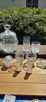 Photo showing the full set of lead crystal items outdoors on wooden table including biscuit jar, shakers, cream and sugar bowl, and glasses.