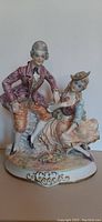 Full front view of the Capodimonte figurine showing the seated man and woman on the ornate base.