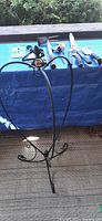Photo of the wrought iron hanging basket frame and garden tools arranged on a blue tarp.