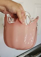 Front side view of pink Murano glass bowl showing smooth curved surface and clear glass decorative edge.