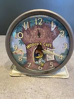 Front view of Woody Woodpecker Woody's Cafe alarm clock showing colorful dial and numerals.