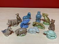 Twelve Wade Red Rose Tea ceramic figurines arranged on a wooden surface against a red background, including animals and a human figure.