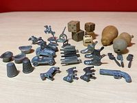Metal vintage Monopoly player pieces arranged with wooden dice and wooden pear-shaped objects visible