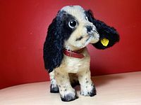 Front-left angle view of original Steiff mohair spotted dog showing black and white fur, big eyes, red collar, and yellow tag in ear