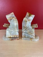 Front view of the pair of onyx monk bookends against a red background.