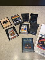 View of all 8 Atari game cartridges and the Star Master instruction manual sealed in plastic.