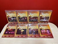 Front view of all 8 sealed Midnight Special DVDs arranged in two rows against a red background, showcasing their distinct cover art and years.