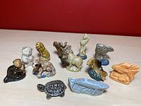 Set of 12 small vintage ceramic figurines from Wade's Red Rose American Series displayed on a table from front angle. Various animal shapes including bear, eagle, fish, lobster, and turtle.
