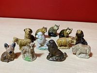 Twelve Wade Red Rose Tea porcelain animal figurines including dog, cat, and farm animal figures arranged on a surface with a red backdrop.