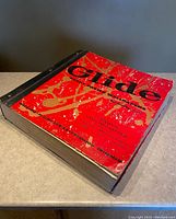 Front cover of the Glide wallpaper sample book showing wear and tear with red and gold splatter design and black text.