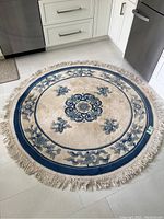 Full view of the round wool area rug showing the entire design and fringed edges in a kitchen setting.