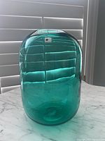 Front view of the teal Blenko glass vase showcasing its translucent color, rounded cylindrical shape, and smooth glossy finish.