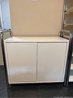 Front view of the white MDF door cabinet with chrome tubular side framing.