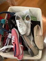 Photo showing white Geox running shoes, red and white Keds shoes, several handbags in various colors, and other items in a white fabric container.