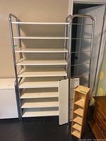 Front view of the large shelving unit with ladder style frame and laminated shelves, and the wooden CD stand beside it.