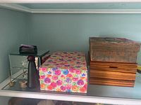 Shelf with four jewelry boxes: mirrored glass, floral print, woodgrain, and decorative pattern boxes visible.
