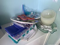 Overview of stacked plastic bowls, plates, napkins, and placemats arranged on white surface