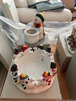 Two ceramic snowman candleholders shown with detailed snowman figures: one single snowman tea light holder and one circular holder adorned with multiple snowmen figures.