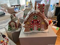 Front side view of the ceramic gingerbread house and schoolhouse showing painted candy and architectural details.