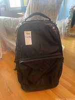 Front view of black Victorinox soft sided suitcase with front pocket and handle on top.