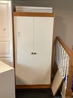 Closed front view of IKEA two-door wardrobe with wooden frame and handles.