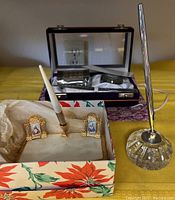 Two desktop pen sets: one with a mother of pearl base and miniature religious portraits, another with crystal cut glass inkwell and silver-tone pen.
