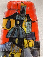 Front view of the glazed ceramic wall plaque showing vibrant abstract architectural design with bold orange, yellow, black and blue hues.