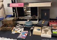 Full view of lot items on display including trinket boxes, watch, jewelry, and kit box