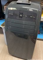 Full view of gray LG portable air conditioner with remote control placed on top.