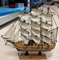 Front angled view of the wooden model ship showing full sails and rigging detail, mounted on wooden base.