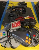Photo showing Nintendo 64 console with controllers, two memory cards, and AV cables.