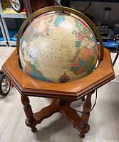 Full view of the Replogle Heirloom globe mounted in an octagonal wooden table stand indoors.
