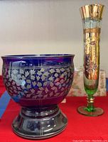 Full view of blue etched glass bowl and hand-painted Arnart bud vase on red cloth with beige background.