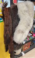 Three vintage fur stoles hanging showing colors and texture: brown, dark brown, and cream.