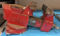 Side view of red metal bench vise showing brand and origin stamped 'CLEVELAND, O. MADE IN U.S.A'.