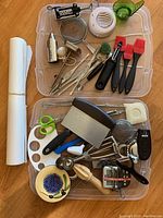 Two plastic bins filled with assorted kitchen tools and paper towels to the left
