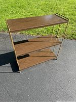 Full view of the three-tier MCM metal shelf unit on asphalt with grass background.