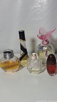 Front view of five perfume bottles showing varying levels of perfume and distinct styles