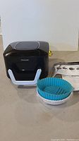 Black and silver Power XL Slimline Air Fryer front view with silicone liners and manual in background.