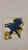 Full view of the ceramic tile trivet featuring the blue bird and yellow flowers
