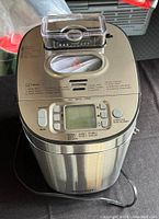 Photo of a stainless steel Starfrit bread maker top and front control panel with digital display and buttons, power cord visible on side.
