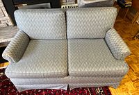 Front view of love seat sofa showing two seat cushions, two back cushions, and rolled arms in patterned fabric.