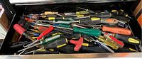 Drawer filled with a variety of screwdrivers and hand tools showing multiple handle styles and colors including Blackhawk brand.